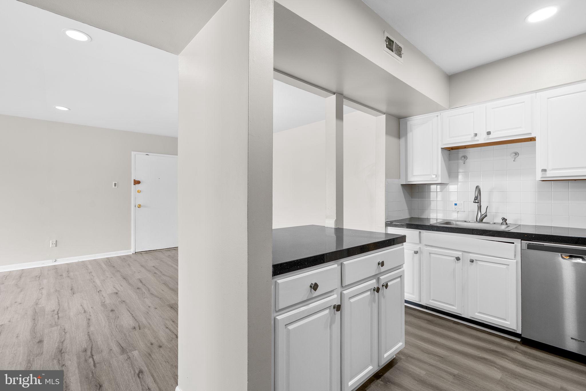 10121 Prince Place, Unit 30210B Upper Marlboro, MD 20774 - Photo 11 of 24 a kitchen with granite countertop white cabinets white appliances and sink