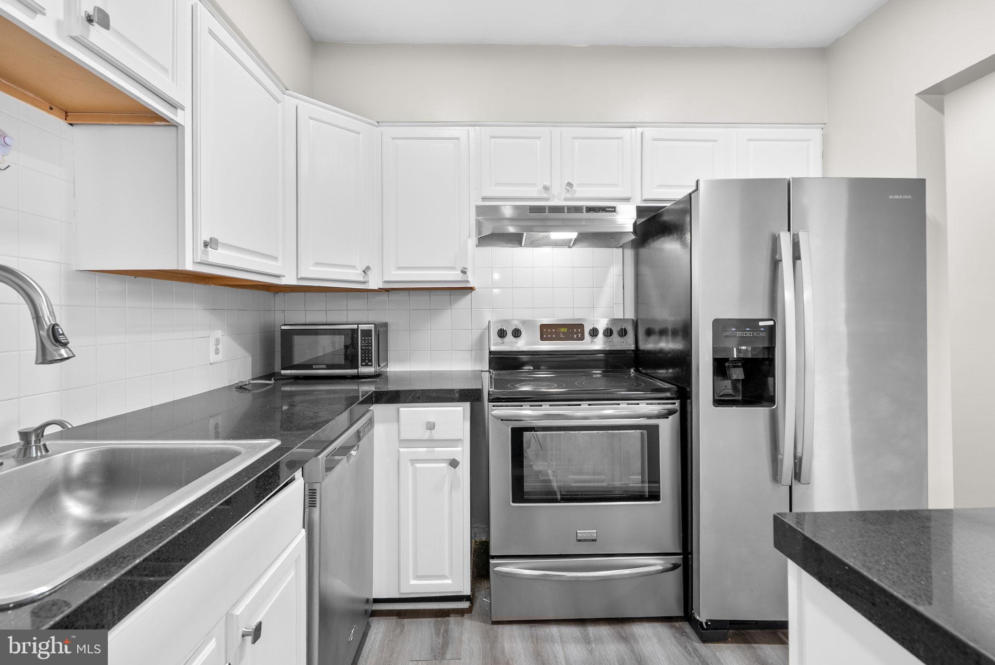 10121 Prince Place, Unit 30210B Upper Marlboro, MD 20774 - Photo 13 of 24 a kitchen with stainless steel appliances granite countertop a sink stove and refrigerator
