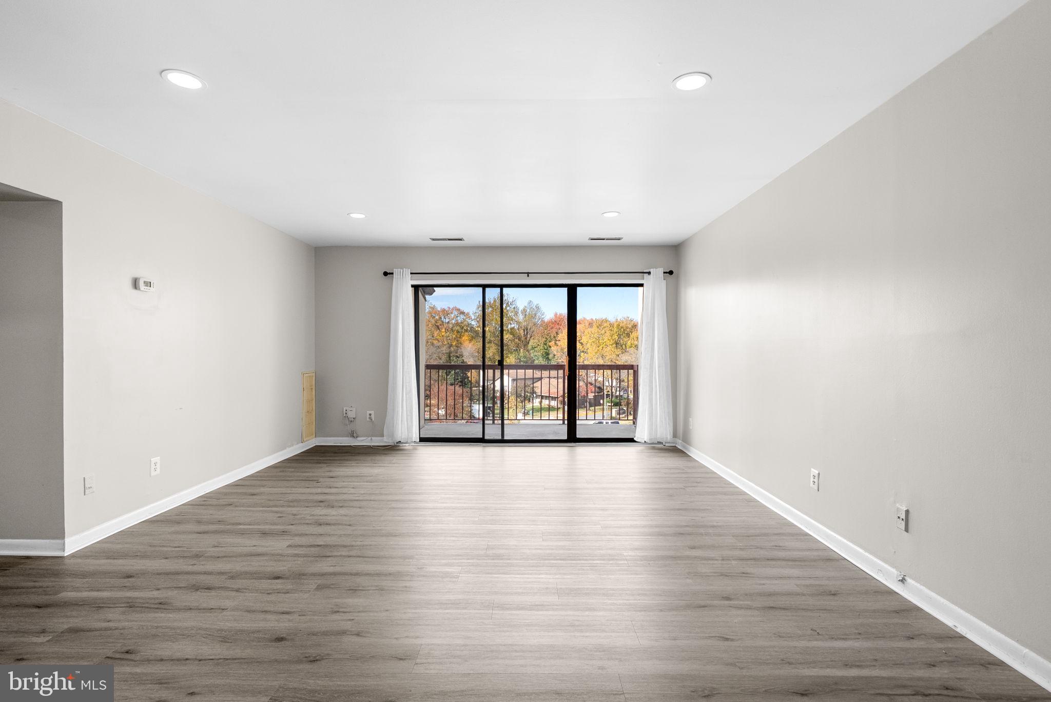 10121 Prince Place, Unit 30210B Upper Marlboro, MD 20774 - Photo 5 of 24 a view of an empty room with wooden floor and a window