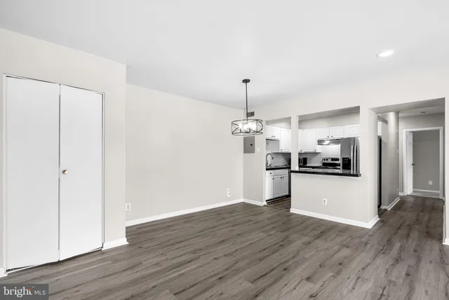 a view of a kitchen and an empty room with wooden floor