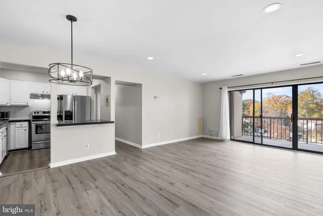 a view of a room with stainless steel appliances wooden floors and kitchen view