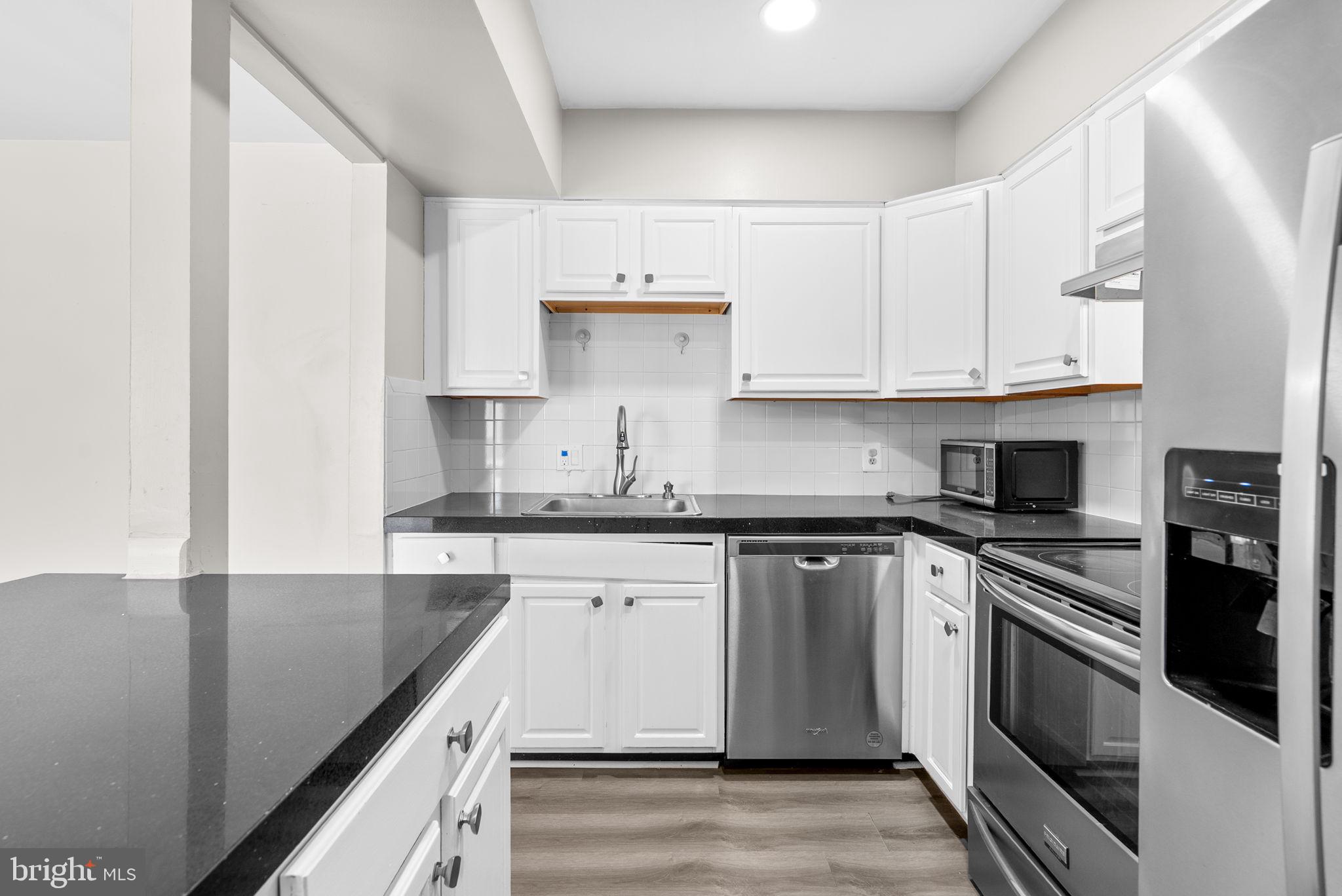 10121 Prince Place, Unit 30210B Upper Marlboro, MD 20774 - Photo 10 of 24 a kitchen with stainless steel appliances granite countertop a sink stove and cabinets