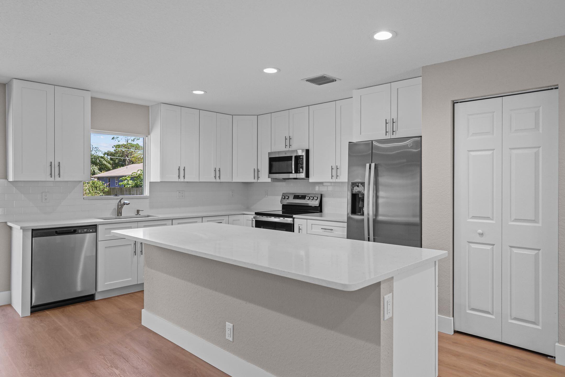 4611 Sunset Boulevard Fort Pierce, FL 34982 - Photo 10 of 28 a kitchen with a refrigerator a sink a stove a microwave and wooden floor