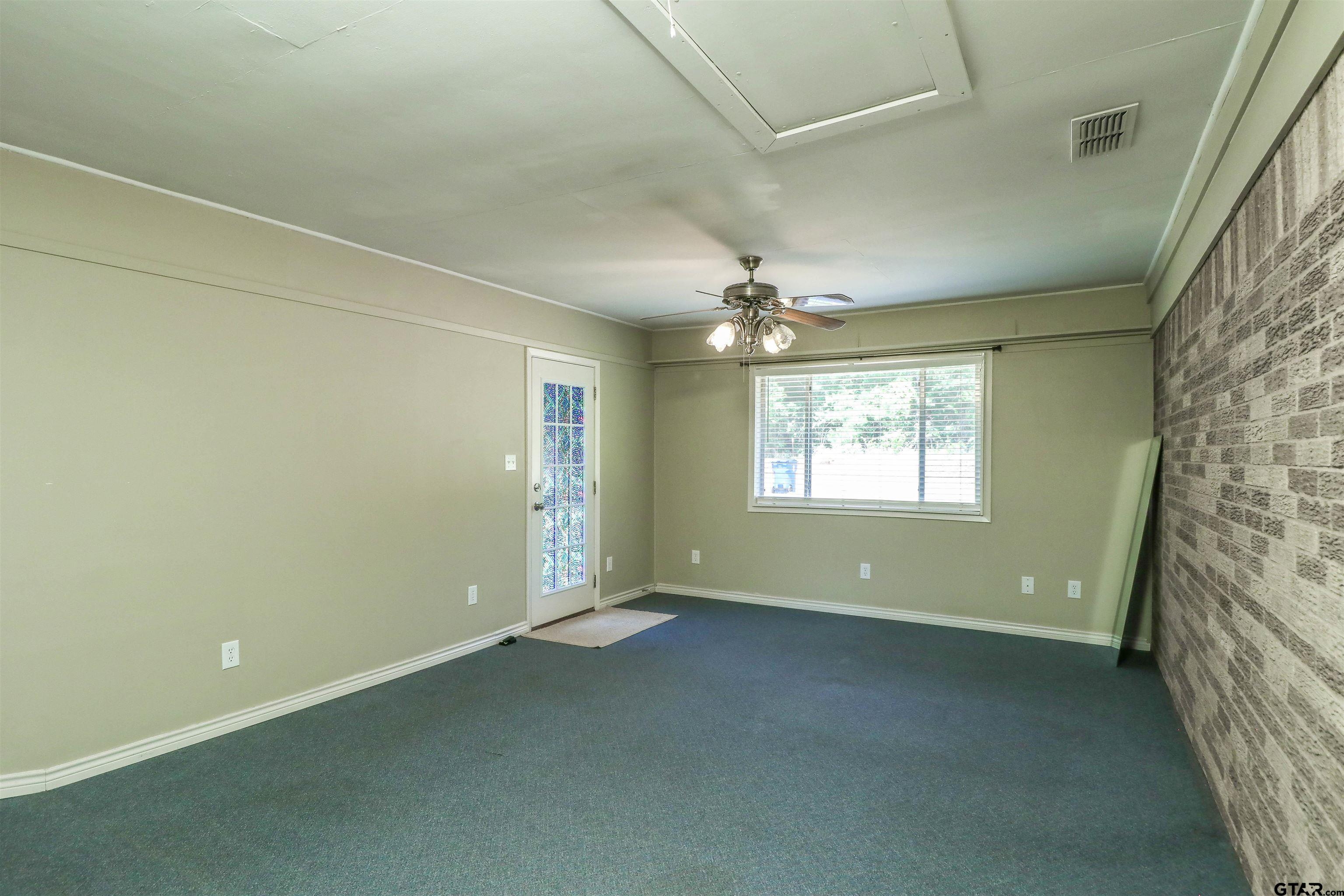 an empty room with a windows and chandelier fan