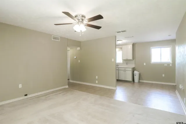 an empty room with windows and fan