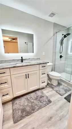 a bathroom with a granite countertop sink toilet and shower