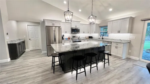 a kitchen with kitchen island granite countertop a sink a center island and stainless steel appliances