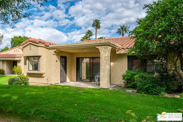 a view of a house with brick walls and a yard with plants