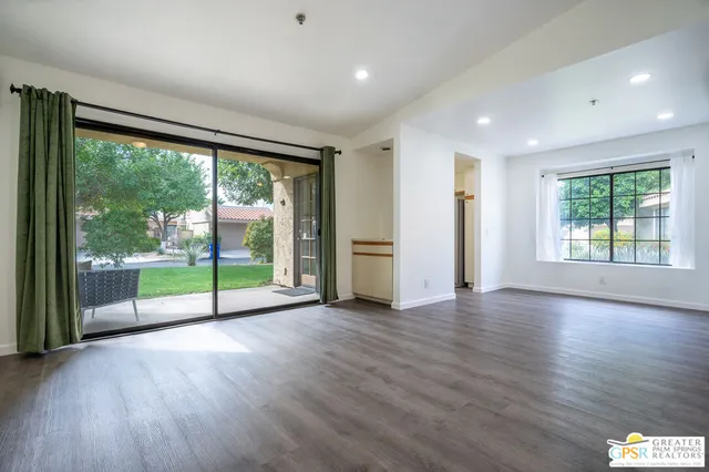 an empty room with wooden floor fan and windows