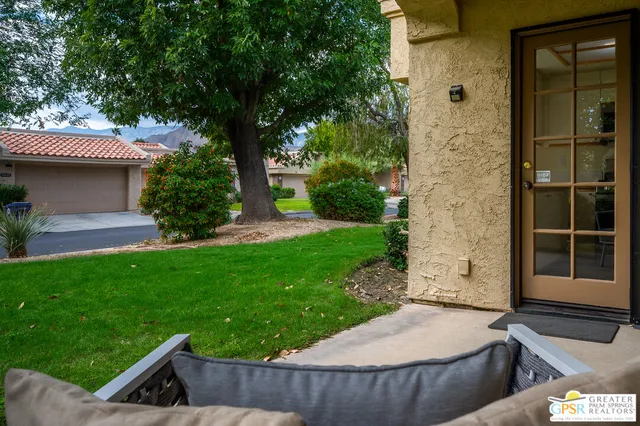 a front view of a house with a garden and a tree