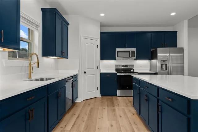 a kitchen with stainless steel appliances a sink dishwasher stove refrigerator and cabinets