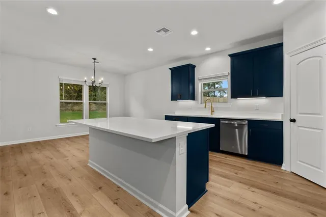 a kitchen with kitchen island granite countertop a sink and a stove top oven with wooden floor