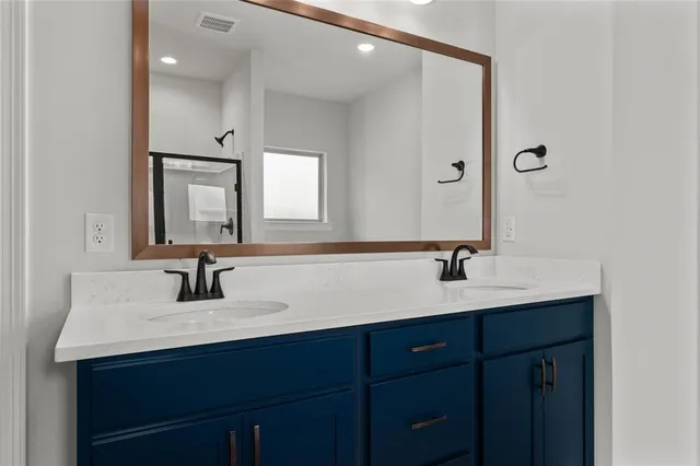 a bathroom with double vanity sinks and a mirror