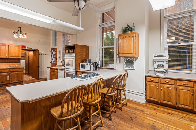 21 North Main Street Kingston, UT 84743 - Photo 68 of 107 Kitchen with wood finish cabinets, light countertops, light wood-type flooring, white appliances, and a peninsula