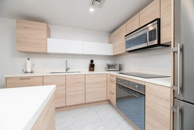 a kitchen with cabinets stainless steel appliances and sink