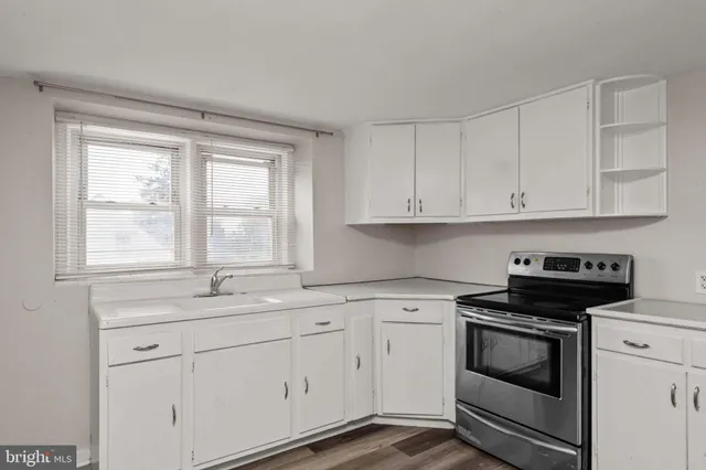 a kitchen with white cabinets appliances a sink and a window