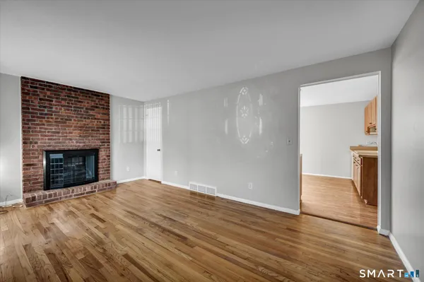 a view of empty room with wooden floor and fireplace