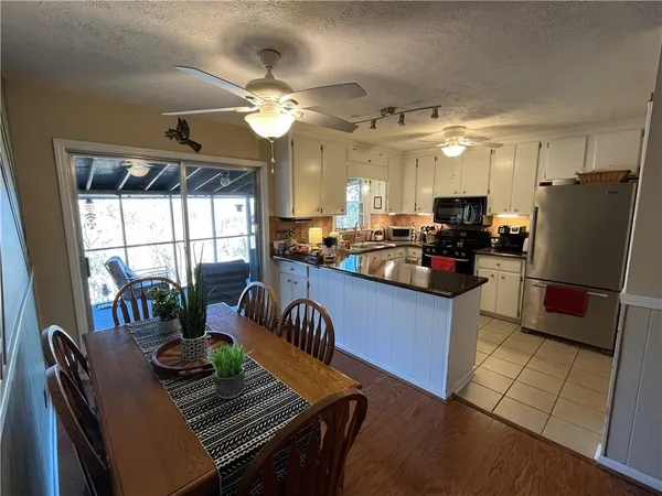 a kitchen with stainless steel appliances granite countertop a stove a refrigerator a sink a dining table and chairs with the view of kitchen