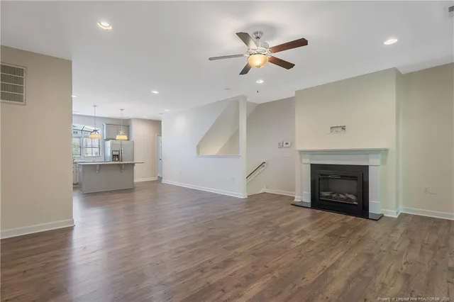 an empty room with wooden floor fireplace and windows