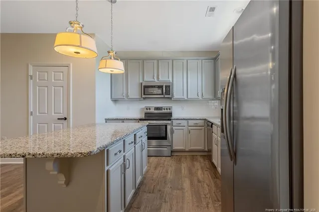 a kitchen with kitchen island granite countertop a stove a refrigerator and a sink