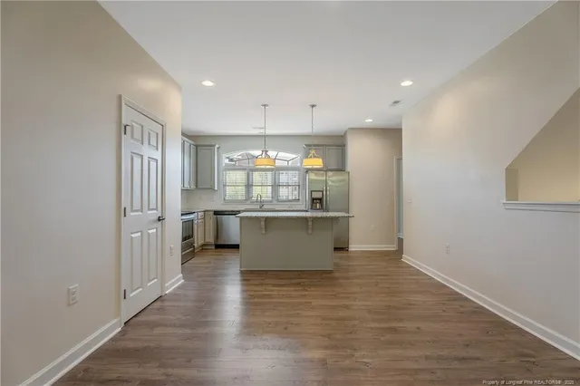 an empty room with wooden floor and a kitchen