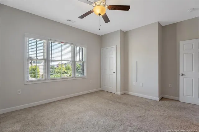 a view of an empty room with window and chandelier fan