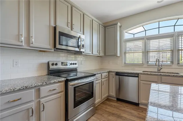a kitchen with stainless steel appliances granite countertop white cabinets granite counter tops and a wooden floors