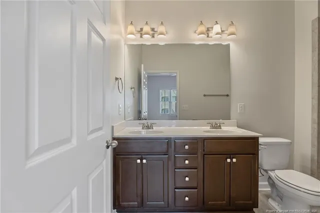 a bathroom with a granite countertop sink a toilet and a mirror