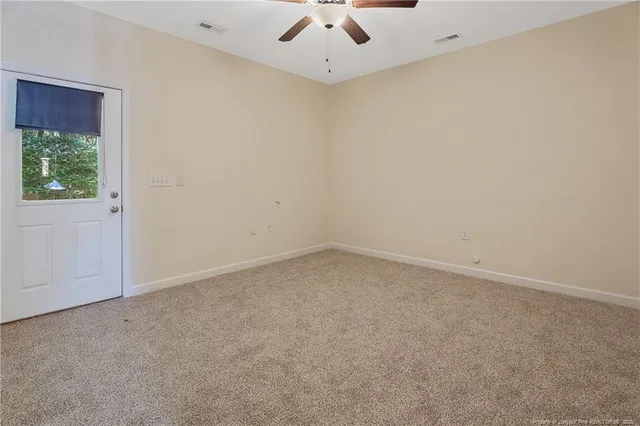 an empty room with a ceiling fan and window