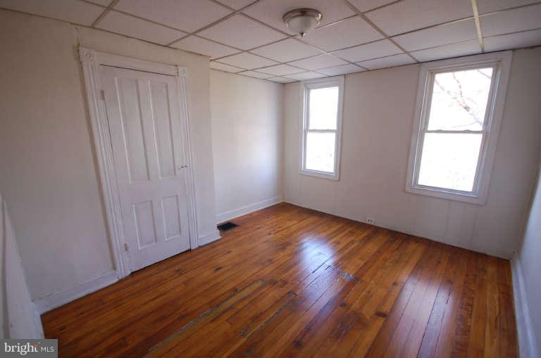 2218 Annapolis Road Baltimore, MD 21230 - Photo 12 of 15 an empty room with wooden floor and windows with curtains