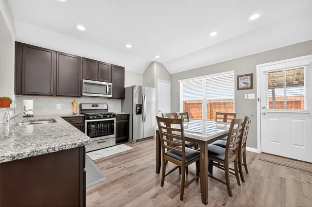 a kitchen with a table chairs microwave and refrigerator