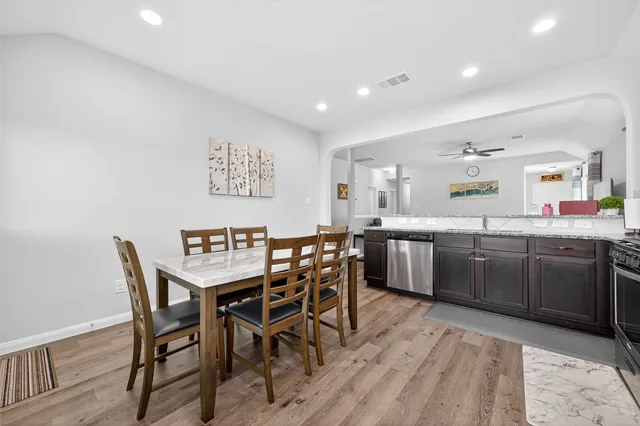 a kitchen with stainless steel appliances kitchen island granite countertop a dining table chairs and a refrigerator
