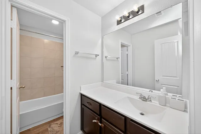 a bathroom with a bathtub shower sink vanity and mirror