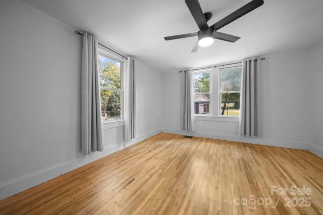 a view of empty room with wooden floor and fan