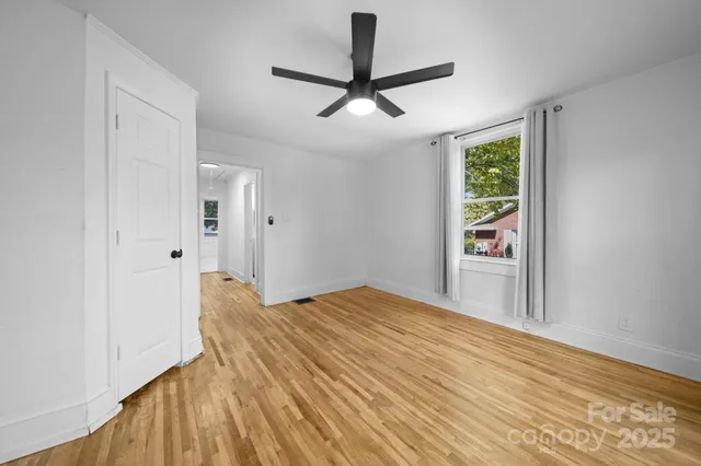 a view of empty room with wooden floor and fan