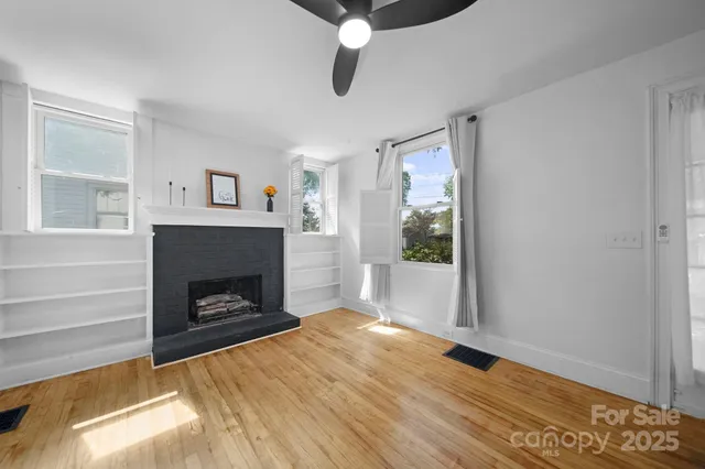a living room with wooden floor and a fireplace