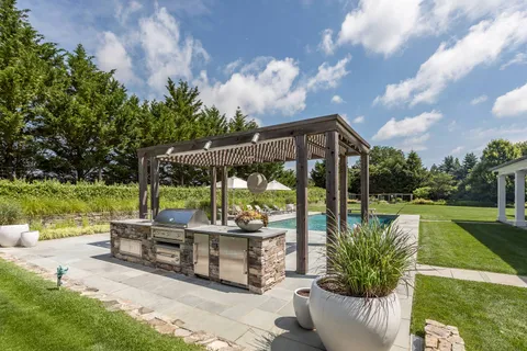 a view of a patio with couches table and chairs under an umbrella next to a yard