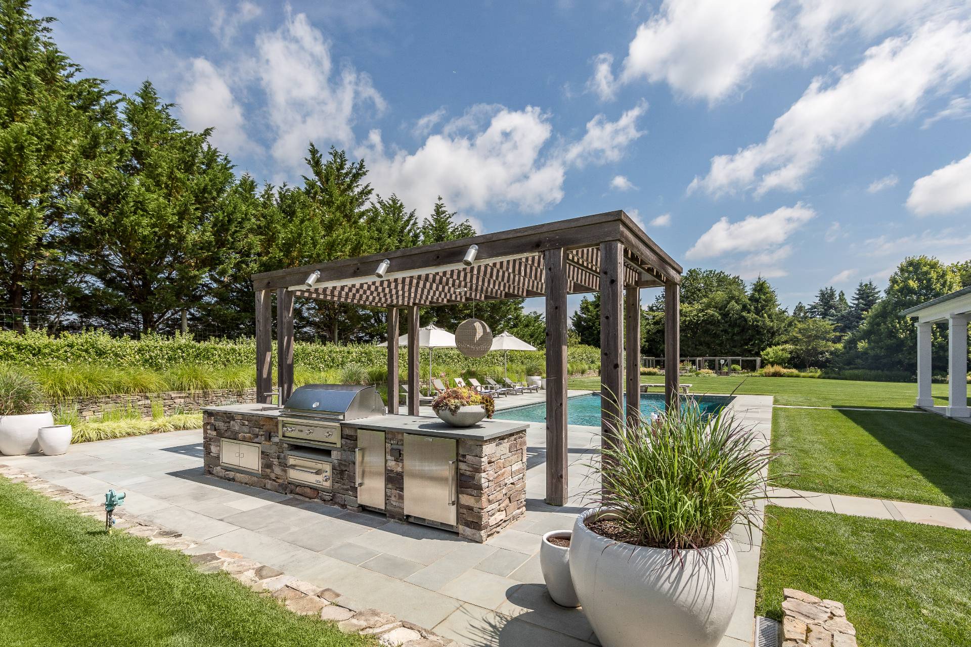 373 Mitchell Lane Bridgehampton, NY 11932 - Photo 5 of 34 a view of a patio with couches table and chairs under an umbrella next to a yard