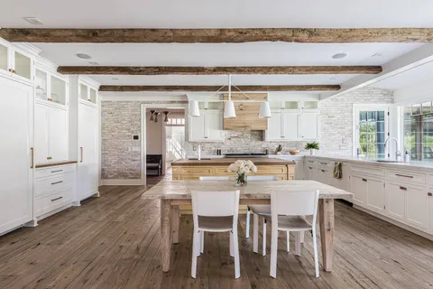 a kitchen with a dining table chairs and white cabinets