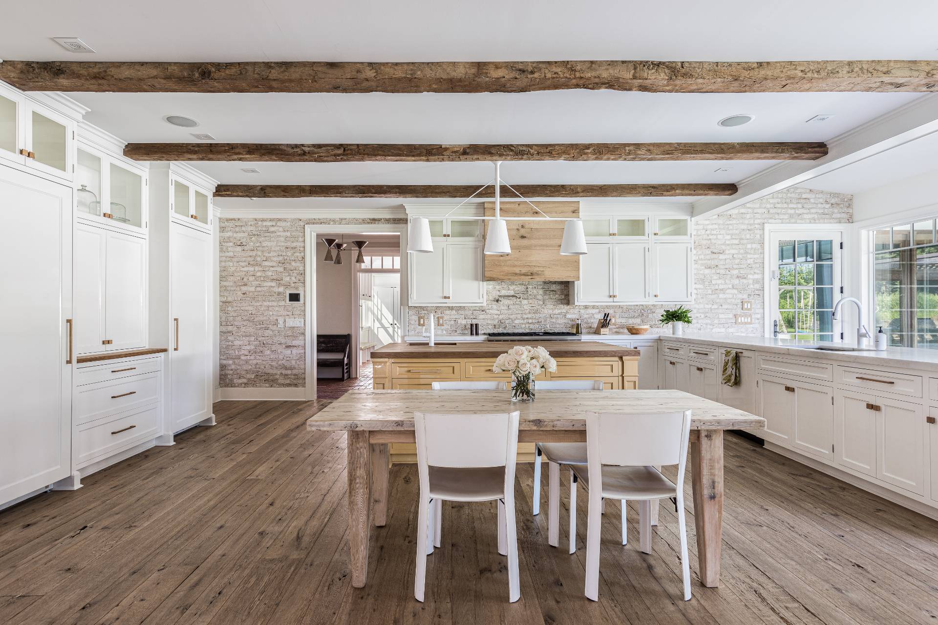 373 Mitchell Lane Bridgehampton, NY 11932 - Photo 7 of 31 a kitchen with a dining table chairs and white cabinets