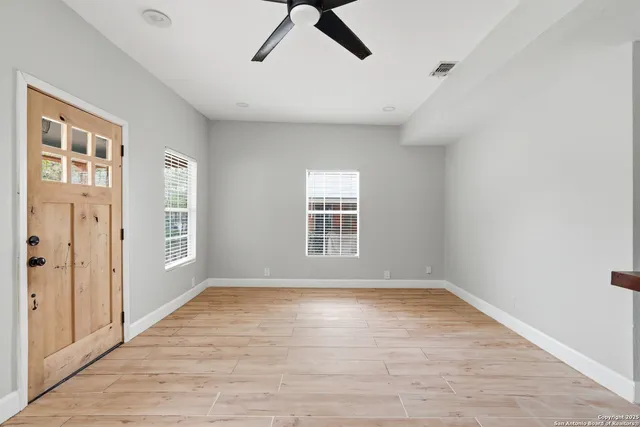 a view of an empty room with a window and wooden floor