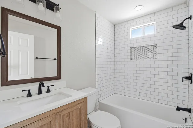 a bathroom with a granite countertop sink toilet and bathtub