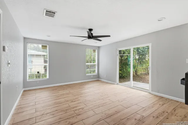 a view of empty room with wooden floor and fan