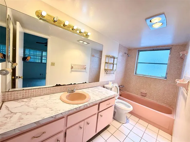 a bathroom with a granite countertop sink mirror vanity bathtub and toilet