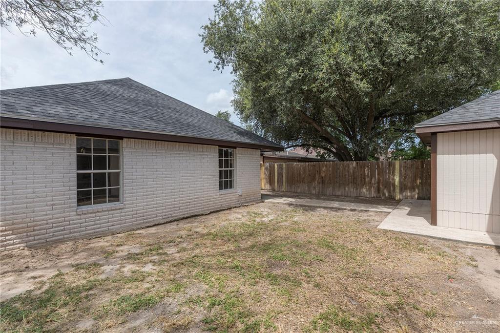 508 Patricia Street Mission, TX 78572 - Photo 22 of 24 Exterior brick construction featuring a dark shingle roof, two grid-pattern windows, and a wood privacy fence