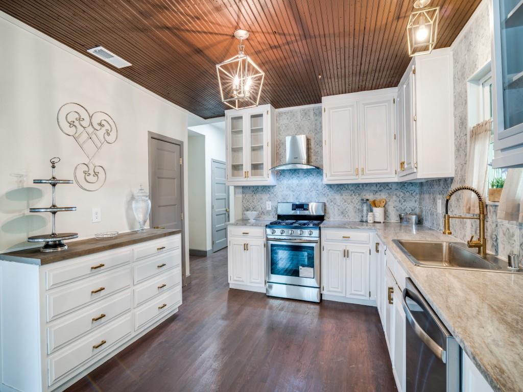 a kitchen with granite countertop a sink a stove cabinets and wooden floor