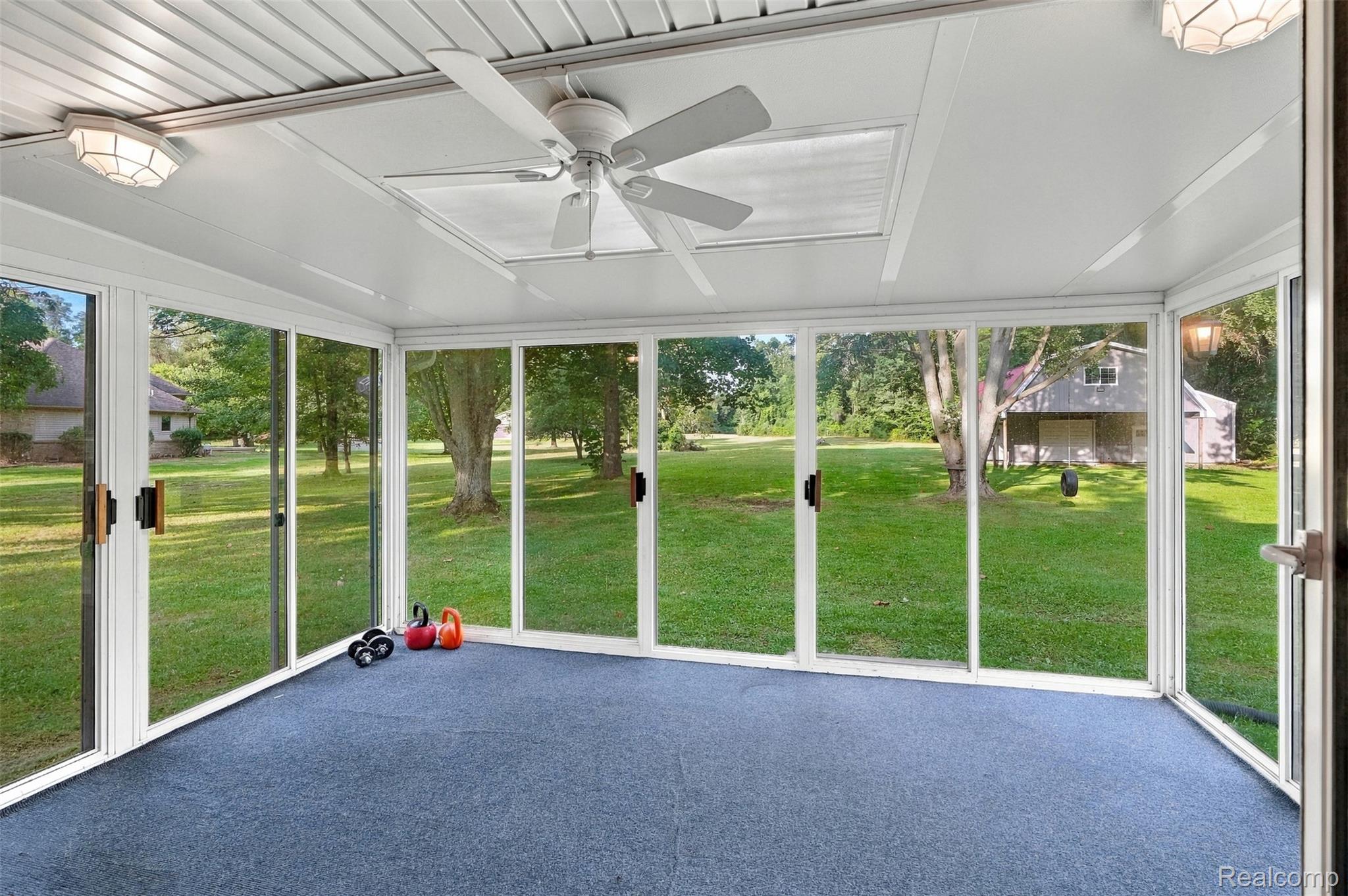 26516 Romine Road New Boston, MI 48164 - Photo 17 of 62 Enclosed sunroom featuring multiple large windows, a ceiling fan, dual overhead light fixtures, and blue carpeting