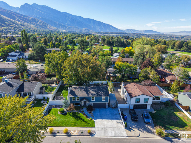 3308 Willow Ridge Road Salt Lake City, UT 84121 - Photo 16 of 59 Striking blue contemporary home featuring a spacious driveway with multiple parking spaces, mature landscaping with established trees throughout the grounds, manicured lawn, and mountain backdrop