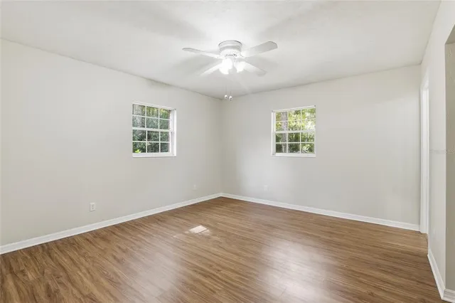an empty room with wooden floor and windows