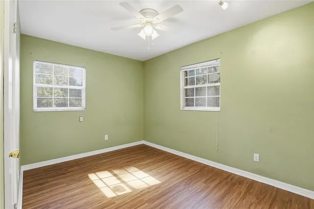 a view of empty room with wooden floor and fan